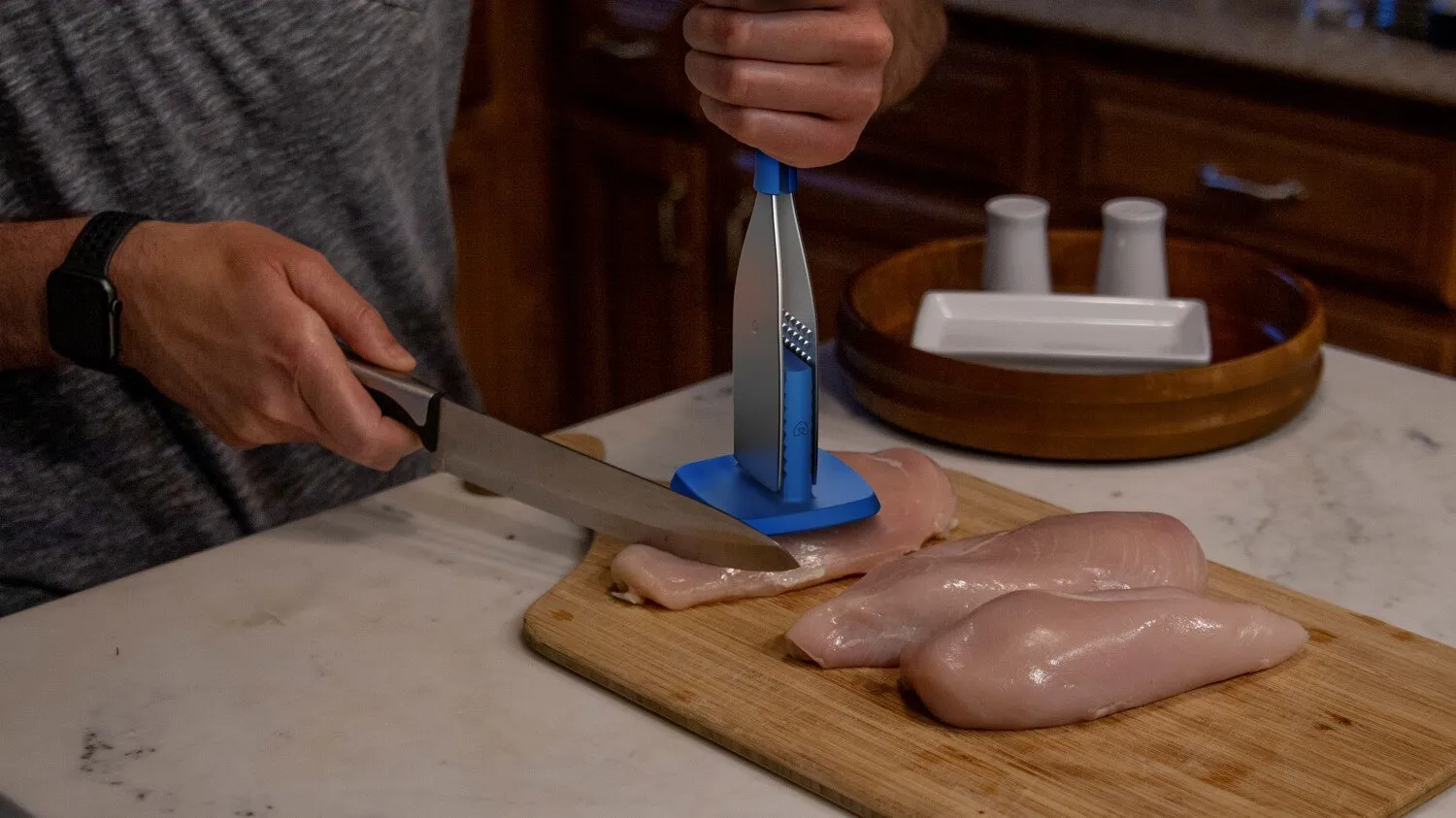 Meat Handler tool holding raw chicken breast on a cutting board during prep
